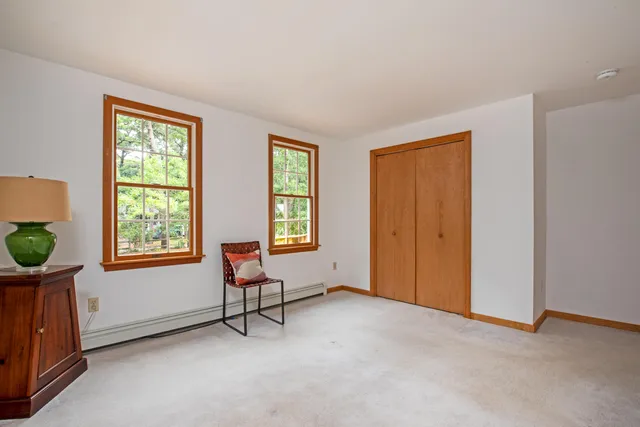 a view of an empty room with windows & lounge chair