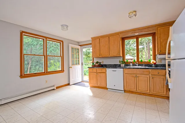 a kitchen with stainless steel appliances granite countertop white cabinets and a window