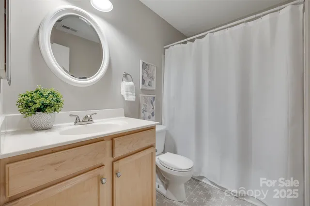 a bathroom with a granite countertop sink vanity mirror and toilet