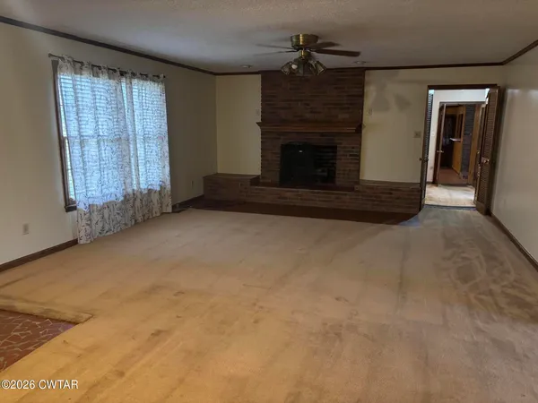 an empty room with windows fireplace and cabinet