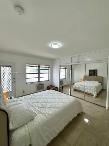 a bedroom with a large bed and windows