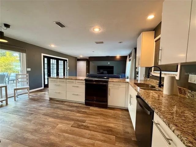 a kitchen with stainless steel appliances granite countertop a stove top oven a sink and a refrigerator