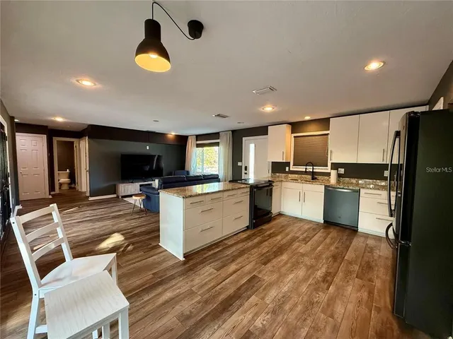 a kitchen with a refrigerator a stove top oven a sink dishwasher and white cabinets with wooden floor