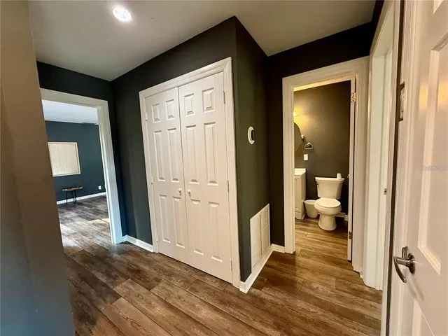 a view of a hallway with wooden floor and a bathroom