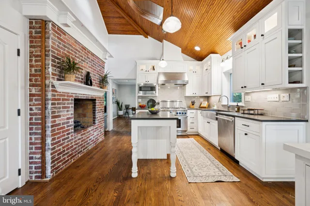 a kitchen with granite countertop a stove top oven a sink dishwasher and white cabinets with wooden floor