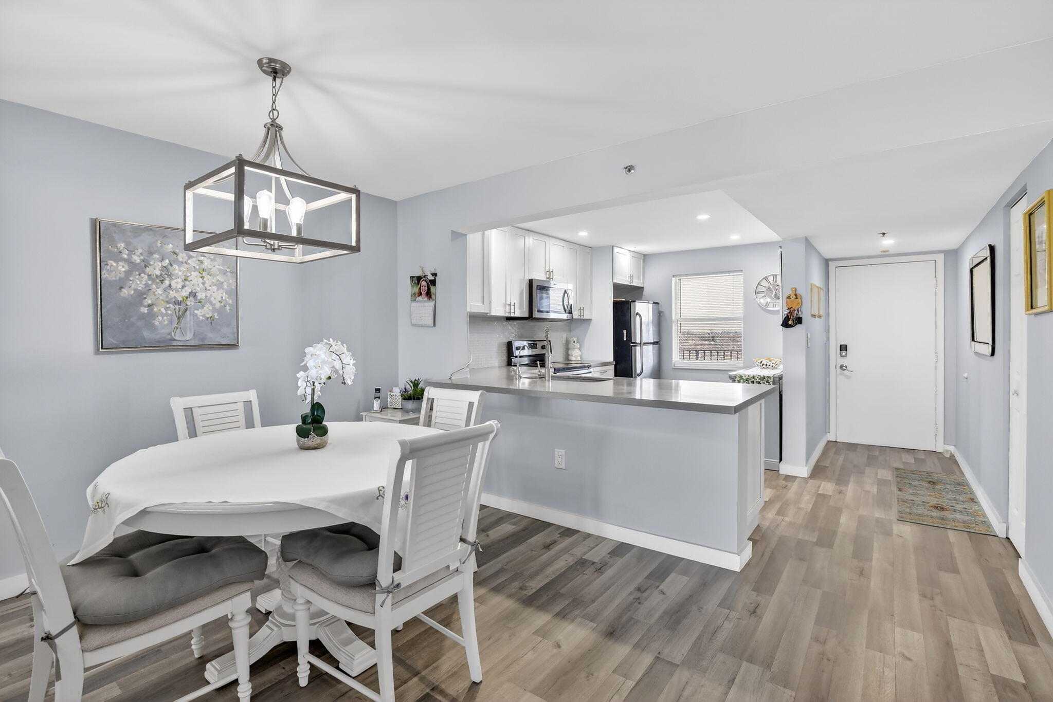 a kitchen with stainless steel appliances kitchen island granite countertop a table chairs and a wooden floor