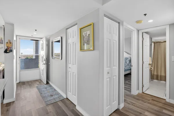 a view of a hallway with wooden floor and a bathroom
