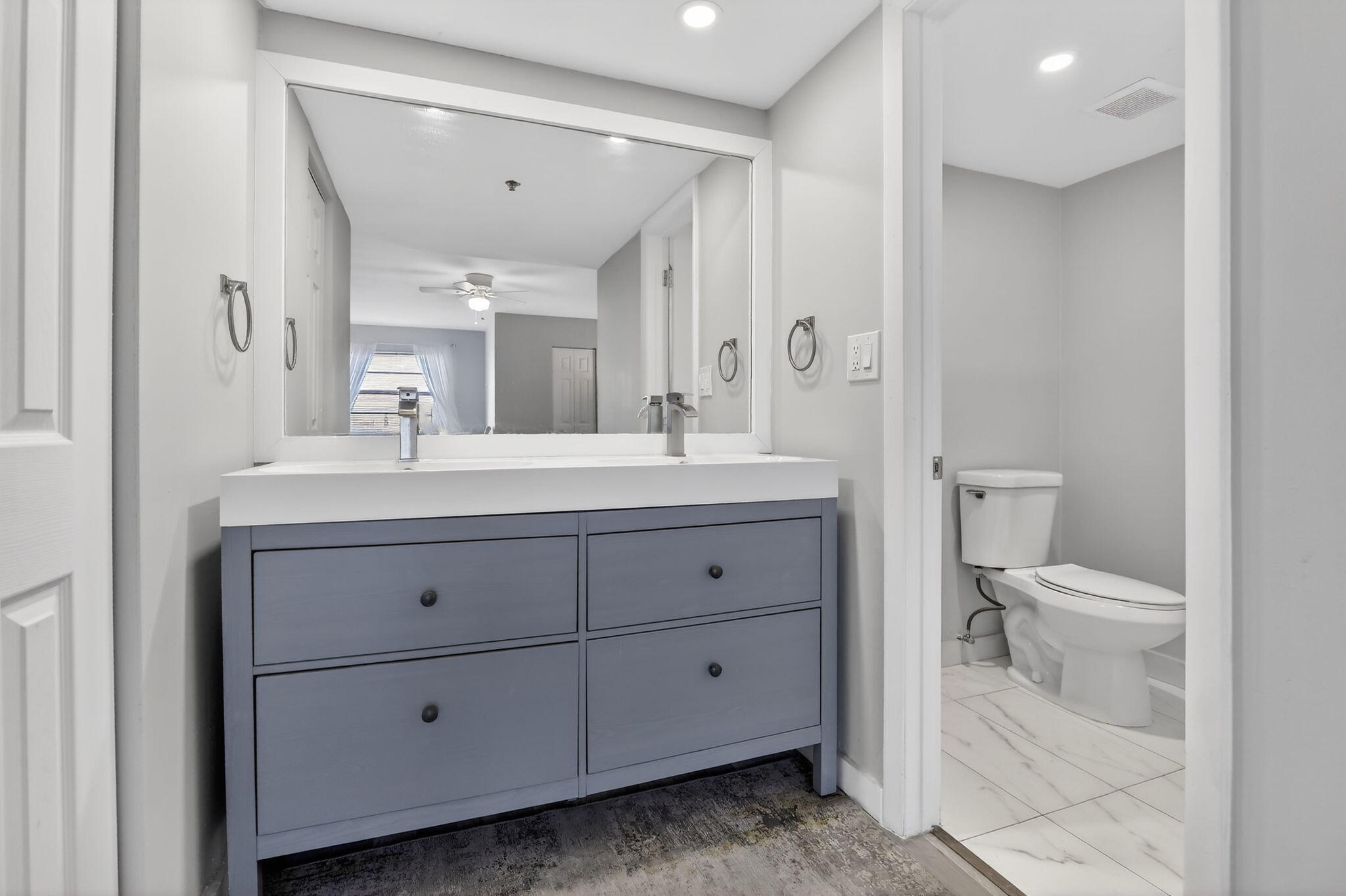 3910 Inverrary Boulevard, Unit 802B Lauderhill, FL 33319 - Photo 20 of 36 a bathroom with a double vanity sink a toilet and a mirror