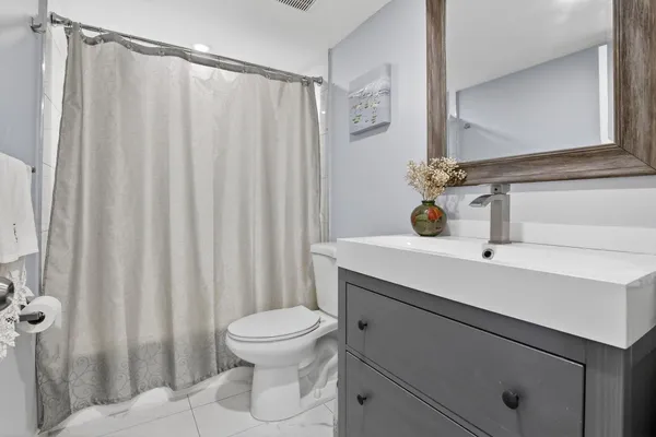 a bathroom with a sink a toilet a mirror and shower curtain