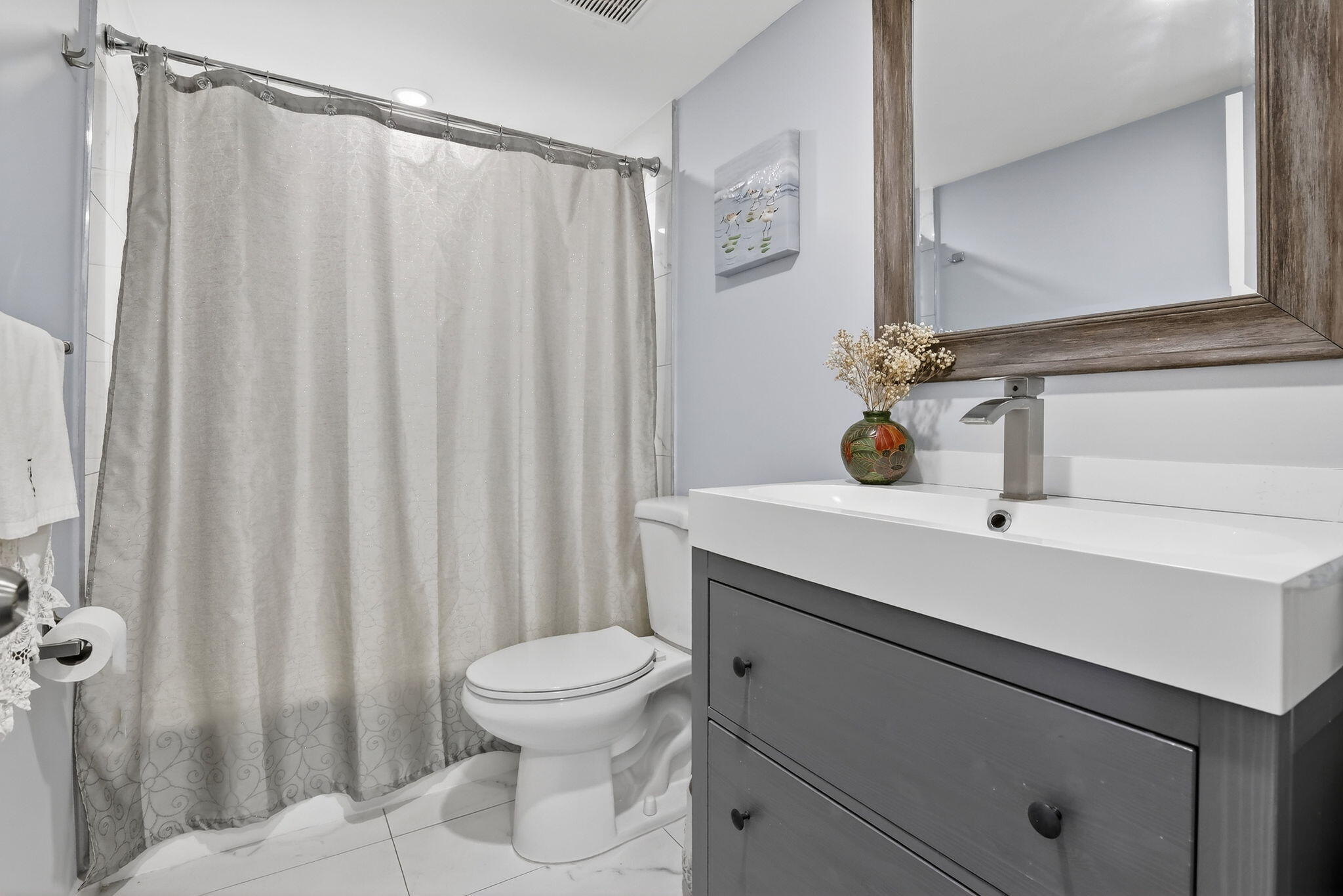 3910 Inverrary Boulevard, Unit 802B Lauderhill, FL 33319 - Photo 24 of 36 a bathroom with a sink a toilet a mirror and shower curtain