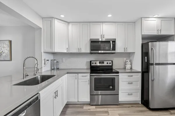 a kitchen with refrigerator a microwave a sink and cabinets
