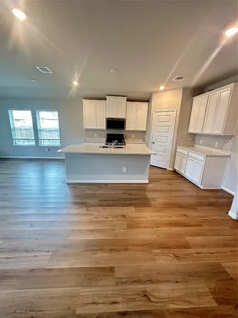 a view of kitchen and empty room with wooden floor