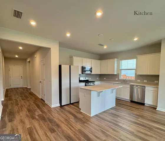 a kitchen with stainless steel appliances granite countertop a stove top oven a refrigerator a sink and a refrigerator