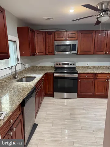 a kitchen with stainless steel appliances granite countertop wooden cabinets a sink and a stove