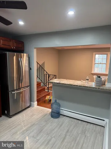 a kitchen with granite countertop a refrigerator and a wooden floor