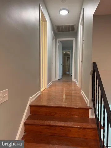 a view of a hallway with wooden floor and stairs