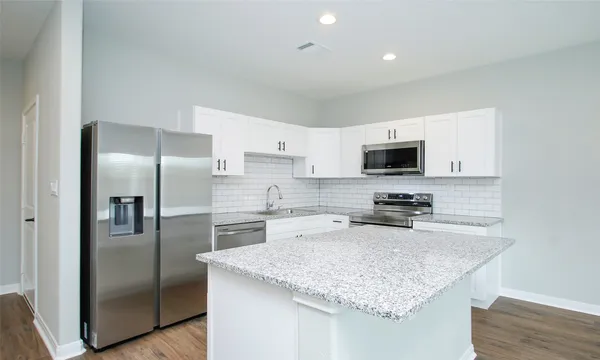 a kitchen with a refrigerator a microwave a sink and cabinets