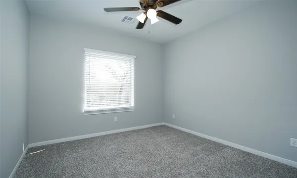 an empty room with a window and a fan
