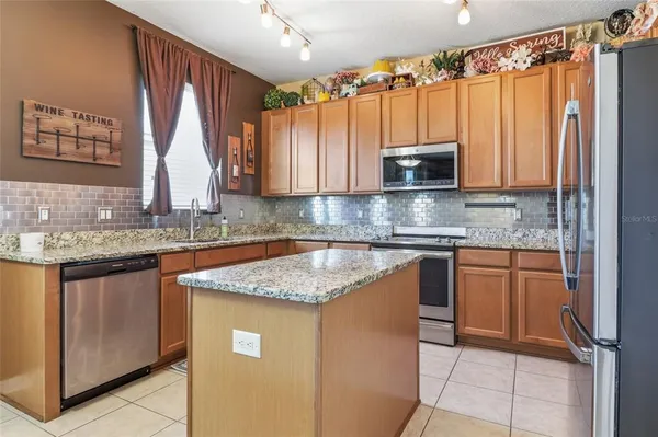 a kitchen with stainless steel appliances granite countertop a sink a stove a refrigerator and cabinets