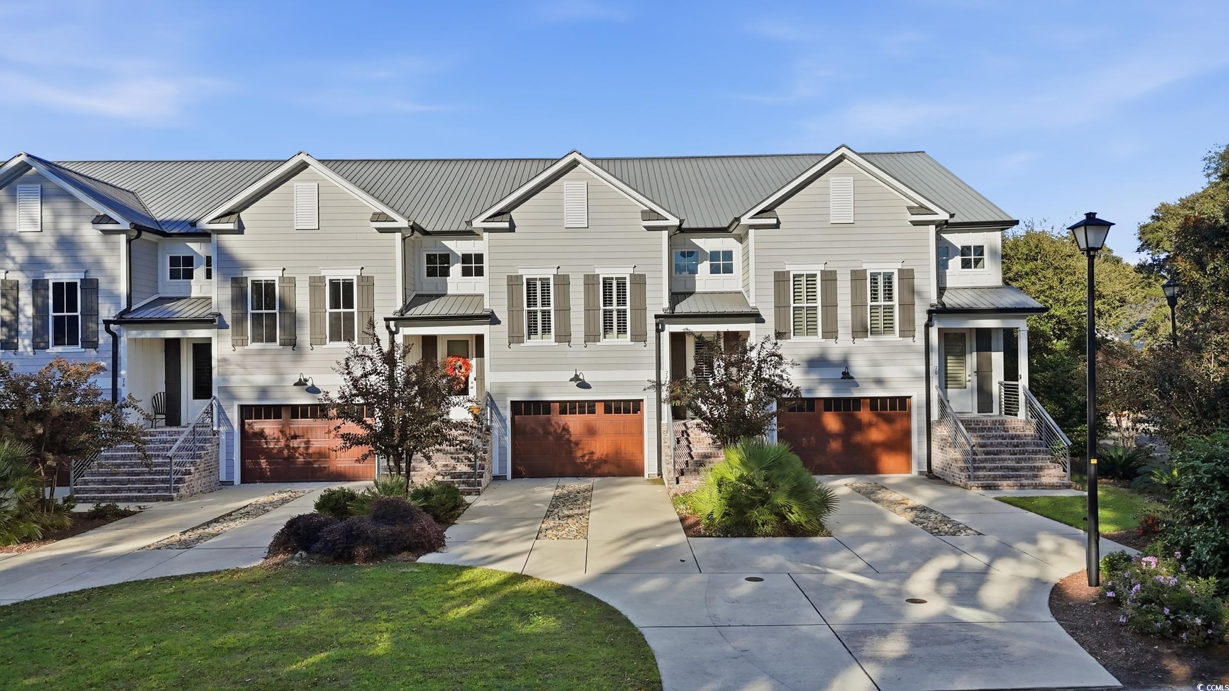 Raised ranch with a metal roof, driveway, an attached garage, and a standing seam roof