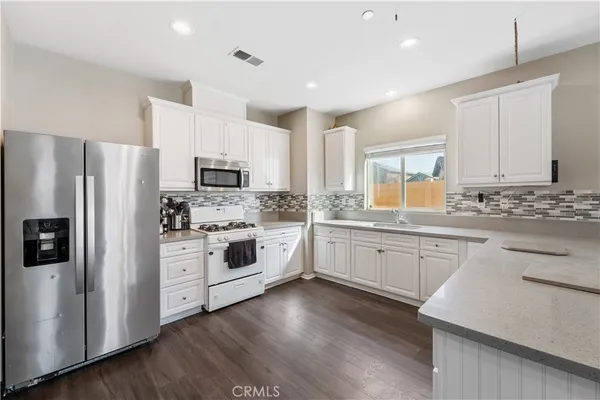 a kitchen with granite countertop white cabinets and stainless steel appliances