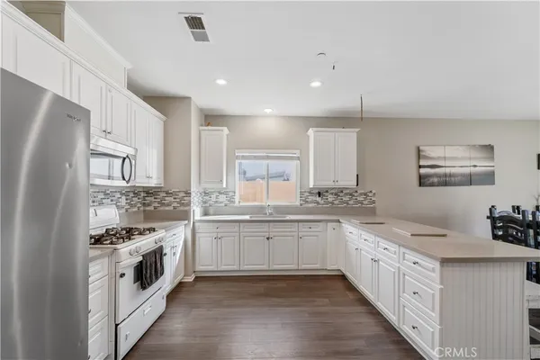 a large white kitchen with stainless steel appliances granite countertop a stove and a sink