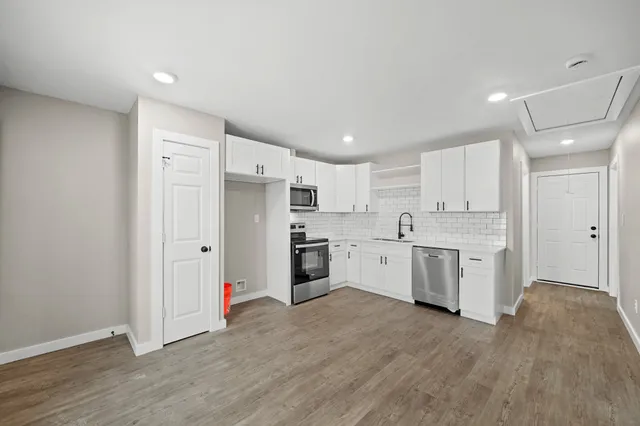a large white kitchen with stainless steel appliances granite countertop a stove and a refrigerator
