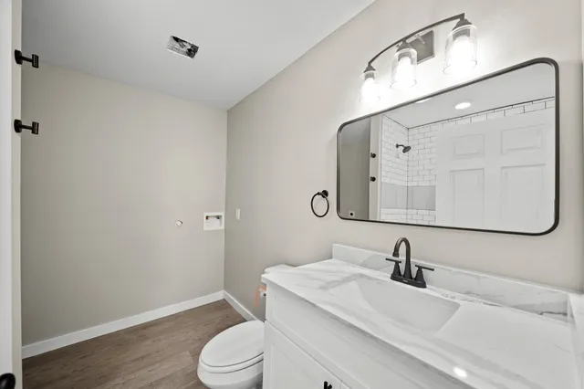 a bathroom with a granite countertop sink toilet and mirror