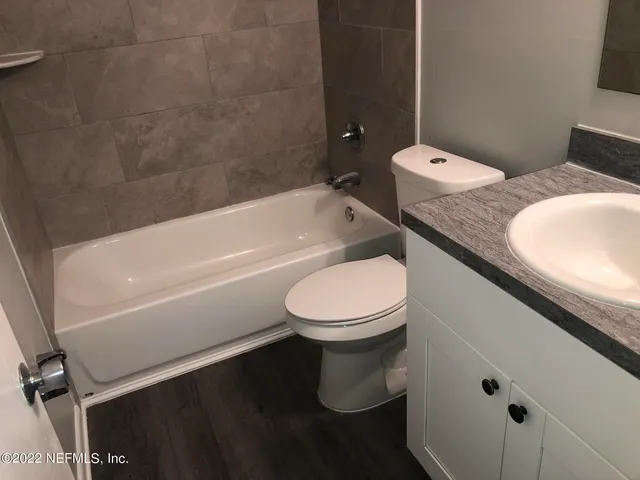 a bathroom with a granite countertop toilet and a bathtub
