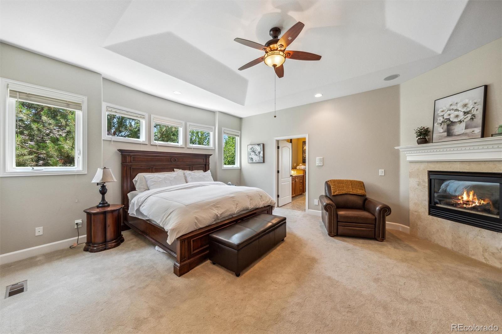 5159 Warbler Court Parker, CO 80134 - Photo 18 of 50 a spacious bedroom with a bed a couch and a chandelier