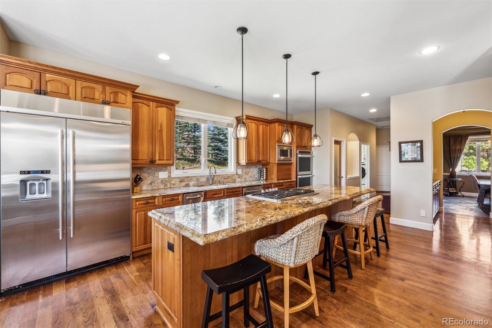 5159 Warbler Court Parker, CO 80134 - Photo 10 of 50 a kitchen with stainless steel appliances granite countertop a kitchen island a stove a table and chairs