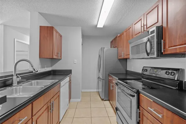 a kitchen with stainless steel appliances granite countertop a sink stove refrigerator and cabinets