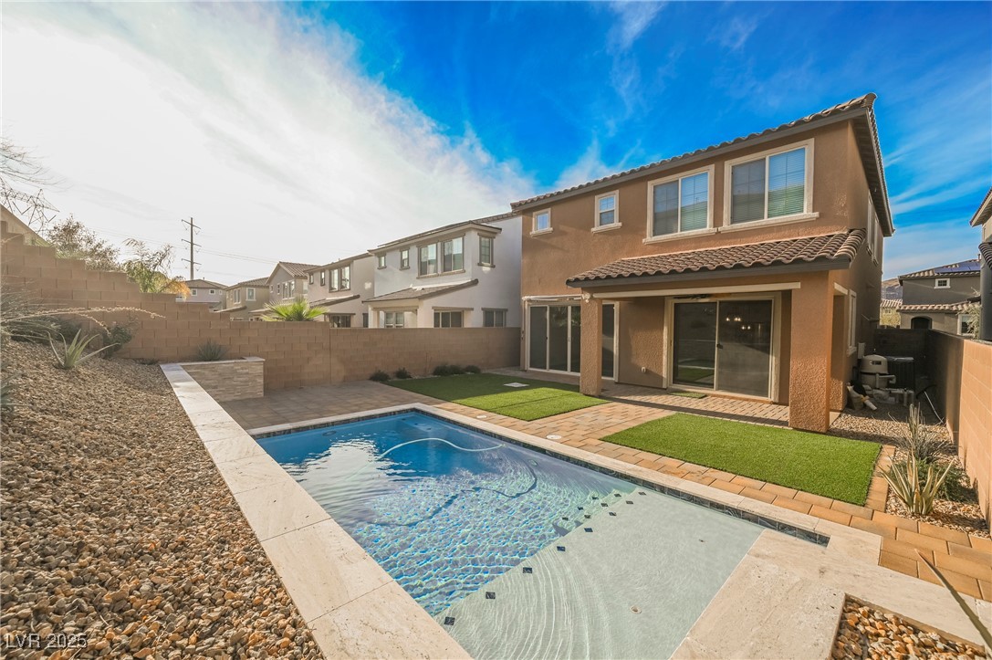 Rear view of house with a patio area, stucco siding, a fenced backyard, a tiled roof, and a residential view