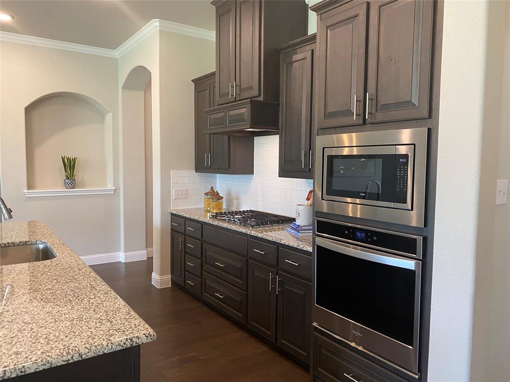 209 Johnson Street Granbury, TX 76048 - Photo 19 of 40 Kitchen with light stone counters, sink, tasteful backsplash, dark hardwood / wood-style flooring, and stainless steel appliances