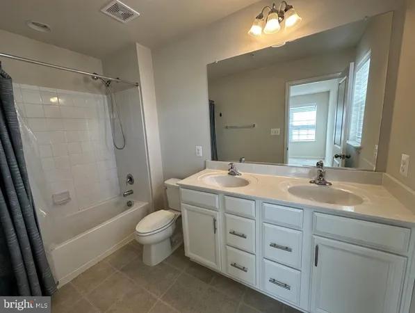 a spacious bathroom with a double vanity sink toilet mirror and shower