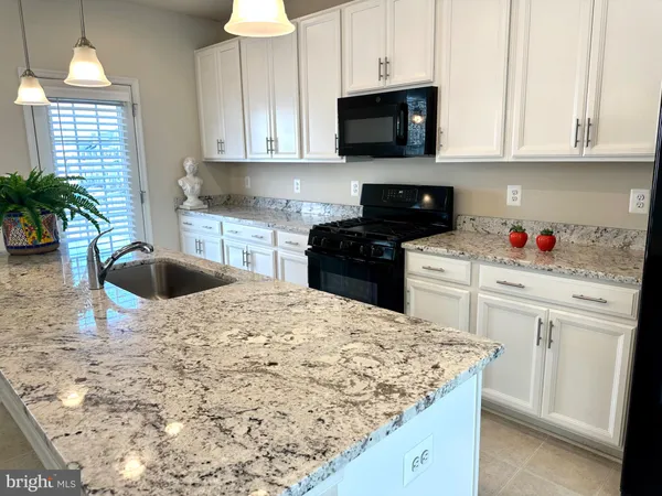 a kitchen with stainless steel appliances kitchen island granite countertop a sink a stove and a microwave