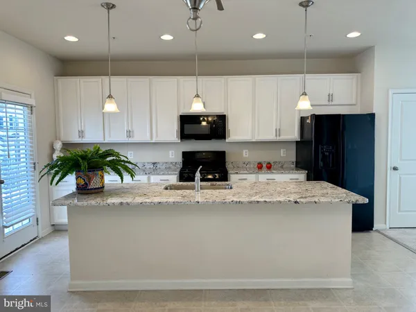 a kitchen with kitchen island a counter top a stove a refrigerator a sink a counter space and a window