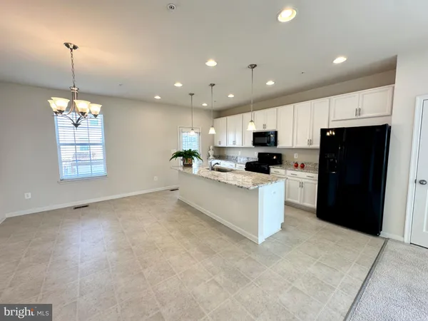 a large white kitchen with kitchen island a sink a center island and stainless steel appliances