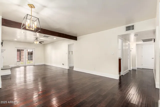 an empty room with wooden floor and chandelier