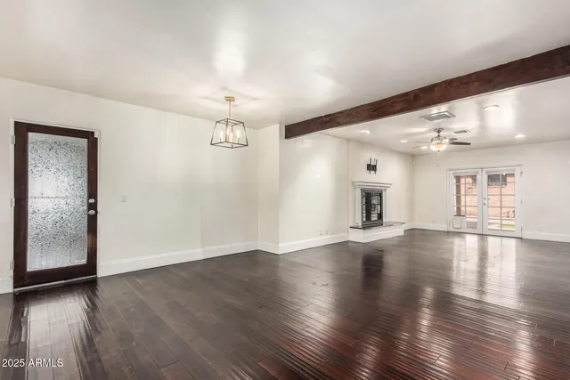 an empty room with wooden floor and chandelier