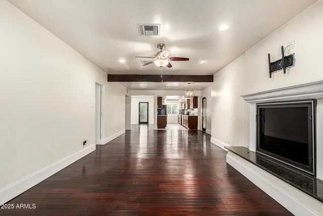 a view of a kitchen with granite countertop stainless steel appliances refrigerator wooden floor and cabinets