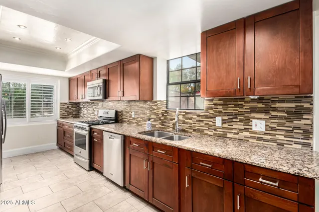 a kitchen with stainless steel appliances granite countertop wooden cabinets a refrigerator and a sink