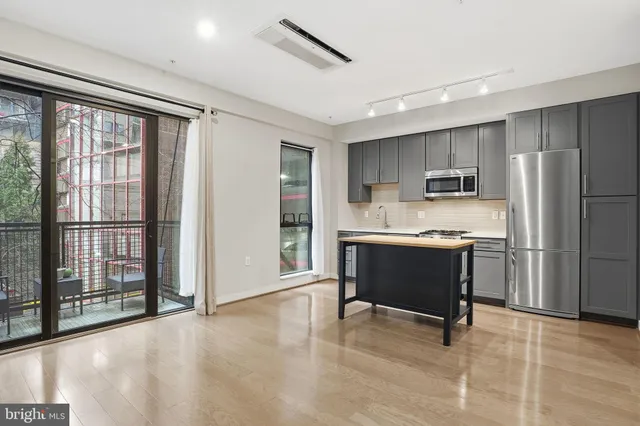 a large kitchen with a refrigerator a stove top oven and a dining table with wooden floor