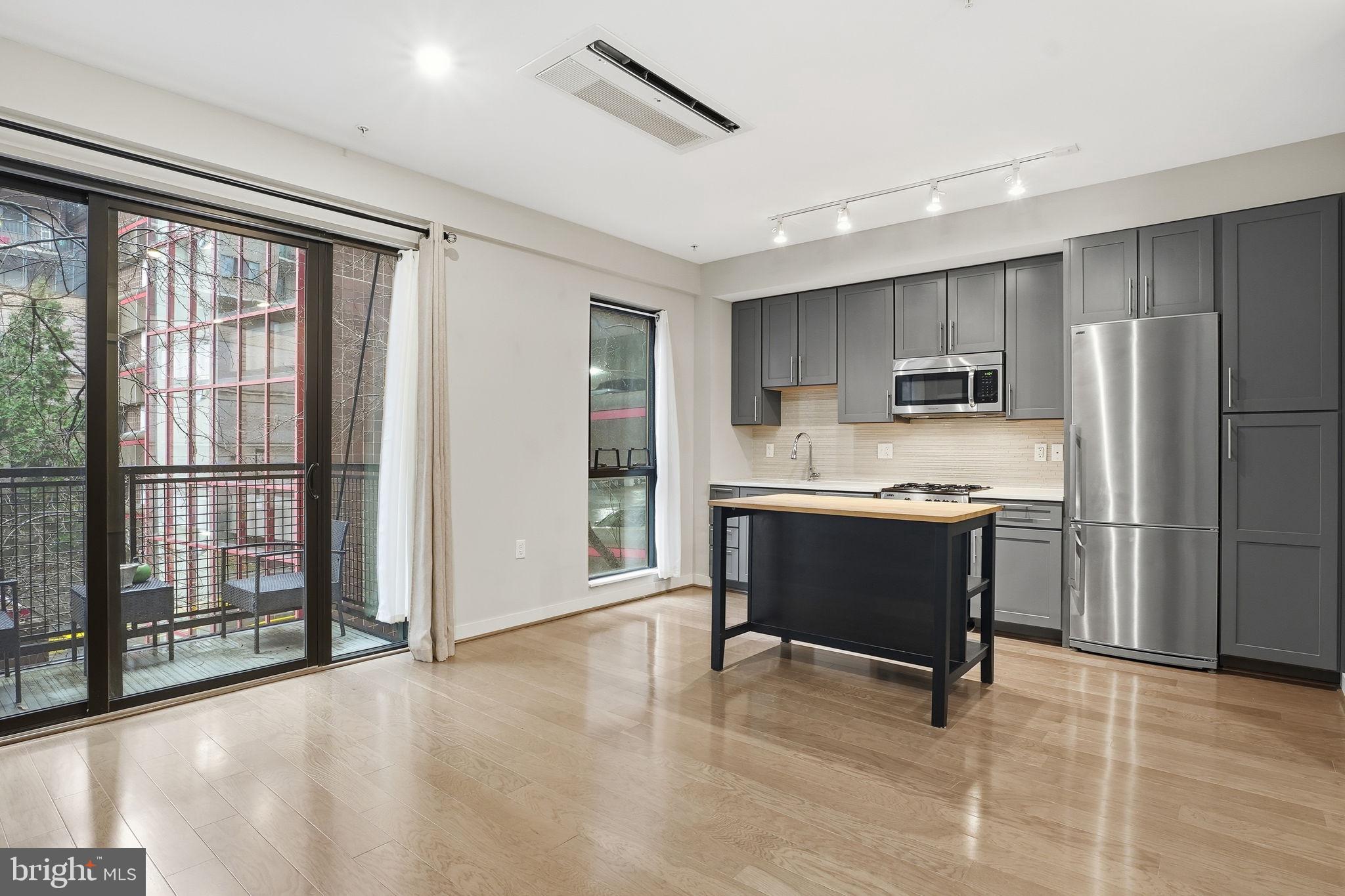 a large kitchen with a refrigerator a stove top oven and a dining table with wooden floor