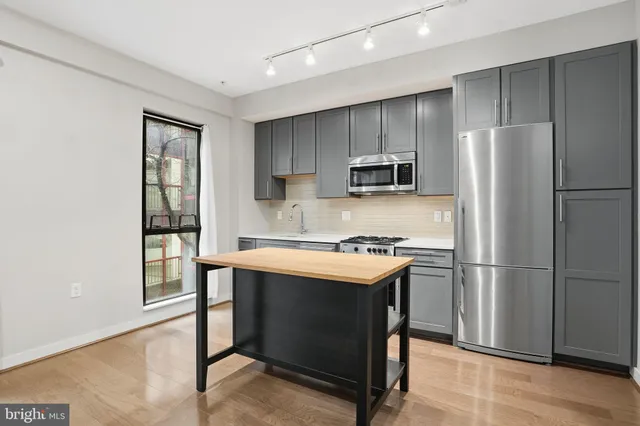 a kitchen with kitchen island a refrigerator stove and microwave