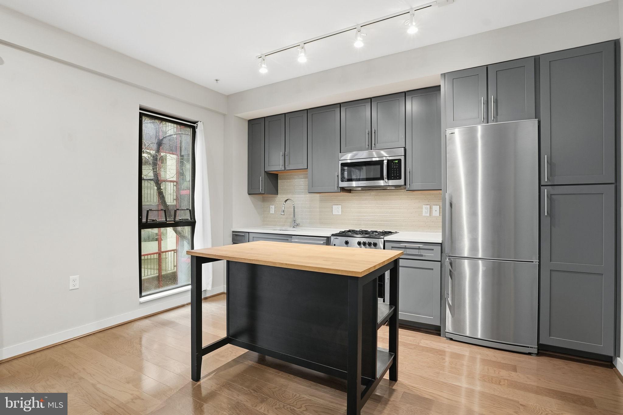 1320 Fenwick Lane, Unit 210 Silver Spring, MD 20910 - Photo 3 of 29 a kitchen with kitchen island a refrigerator stove and microwave