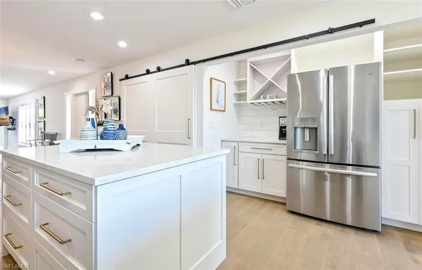 a kitchen that has a lot of white cabinets and wooden floor