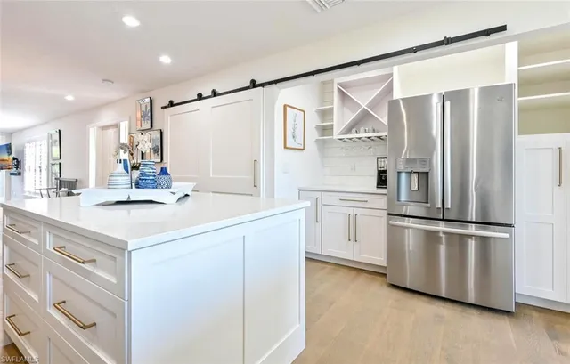 a kitchen that has a lot of white cabinets and wooden floor