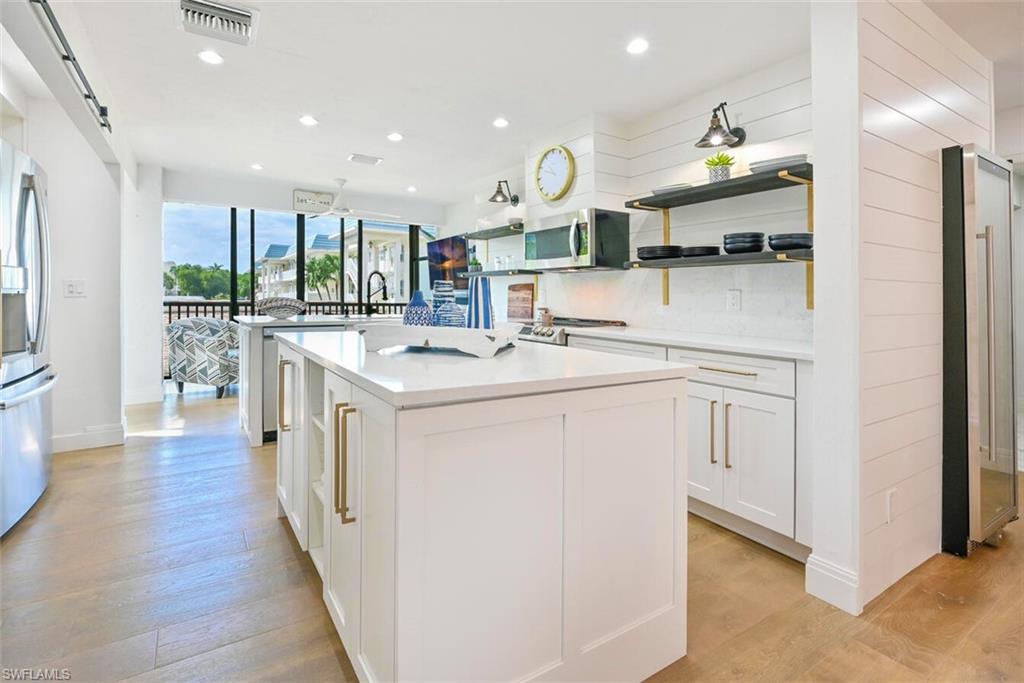 3105 Riviera Drive, Unit A201 Naples, FL 34103 - Photo 14 of 30 a kitchen that has a lot of white cabinets and wooden floor