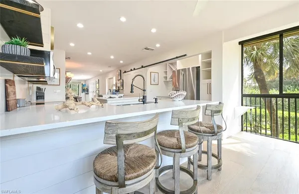 a kitchen with stainless steel appliances kitchen island granite countertop a stove and white cabinets with wooden floor